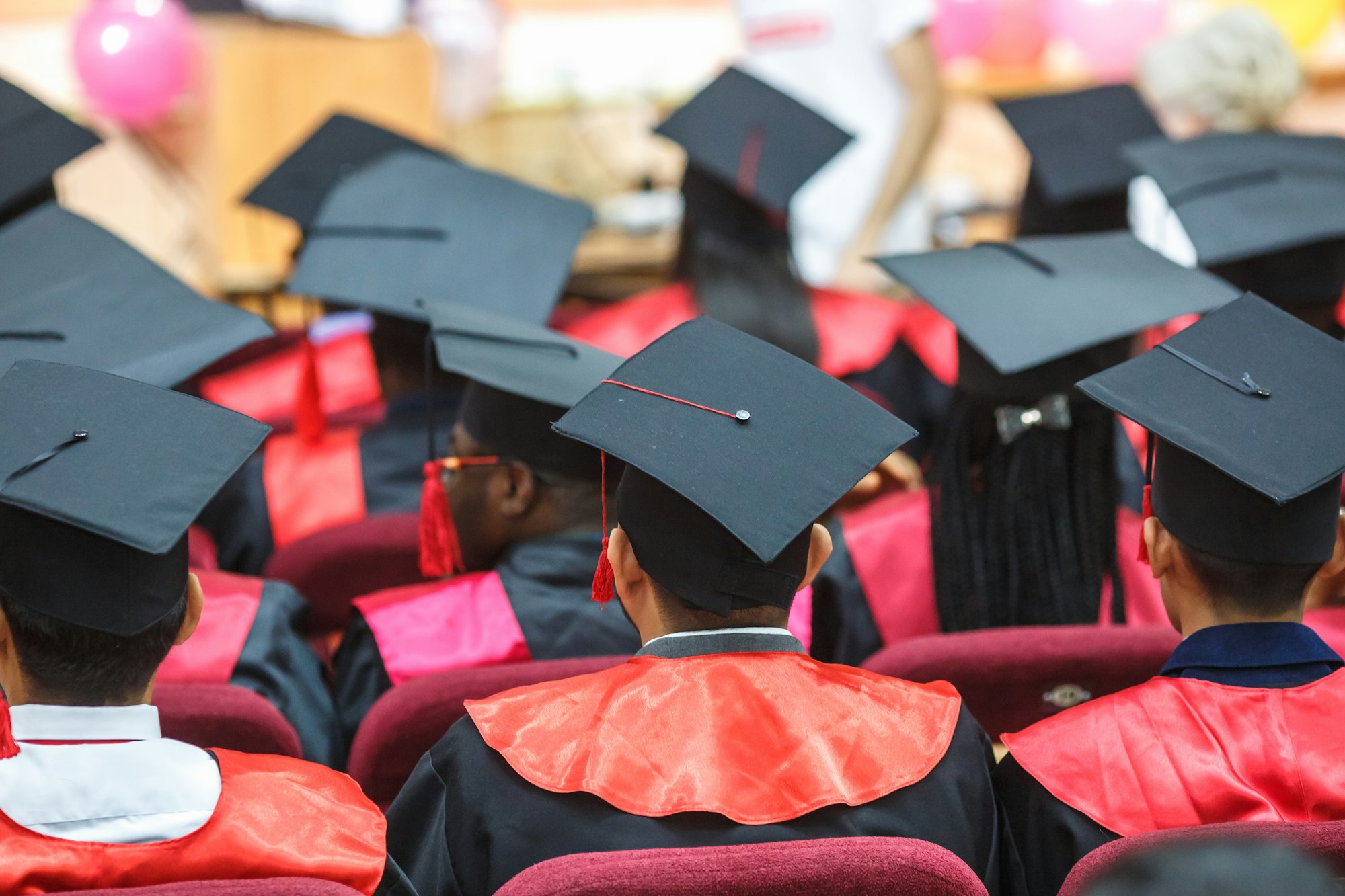 Foreign medical students in square academic graduation caps and black raincoats during commencement